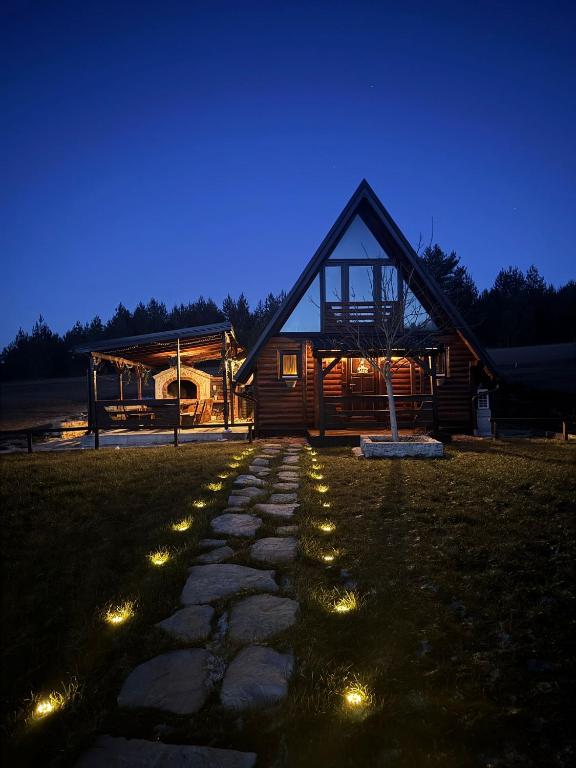 Village House IVA noću, osvijetljena kamena staza kroz livadu